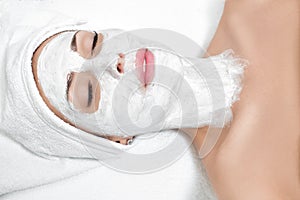 Woman getting facial mask in spa