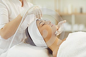 Woman getting facial skin ultrasound cavitation and anti-aging cosmetics from cosmetologist
