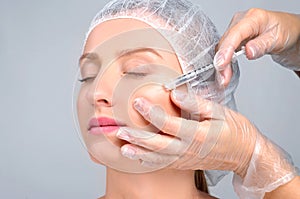 Woman is getting filler injection in cheeks. Anti-aging treatment and face lift. Cosmetic Treatment and Plastic Surgery