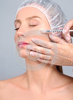 Woman is getting filler injection in cheeks. Anti-aging treatment and face lift. Cosmetic Treatment and Plastic Surgery