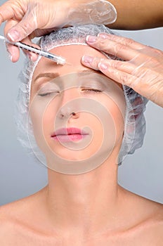 Woman is getting injection in forehead. Anti-aging treatment and face lift. Cosmetic Treatment and Plastic Surgery