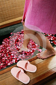 Woman getting into a flower bath. Conceptual image shot