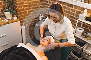 A woman getting a hand facial spa massage in a beauty salon