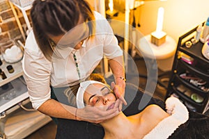 A woman getting a hand facial spa massage in a beauty salon