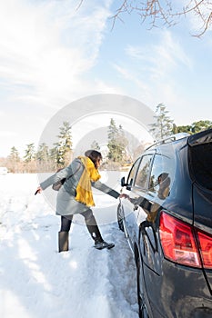 Woman getting into her car on a sunny, snowy winter day