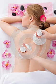 Woman getting herbal compress ball therapy