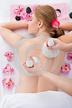 Woman getting herbal compress ball therapy photo