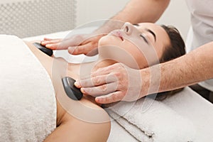 Woman getting hot stones massage at spa salon