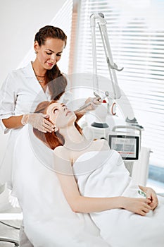 Woman getting laser face treatment in medical center, skin rejuvenation concept