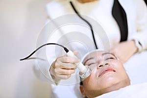 Woman getting laser and ultrasound face treatment in medical spa center. skin rejuvenation concept. woman laying eyes closed, rece