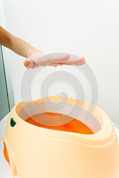 Woman getting paraffin hand treatment at beautician