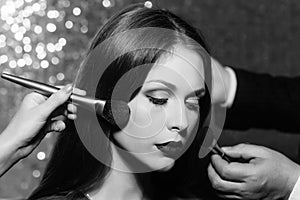 Woman getting powder on face skin with two brushes