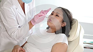 Woman getting procedure of injection contouring and lip augmentation for facial correction in cosmetology clinic