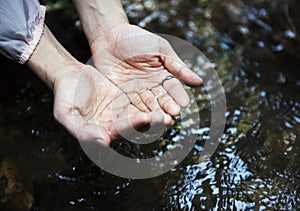 Woman getting some water from the river to drink