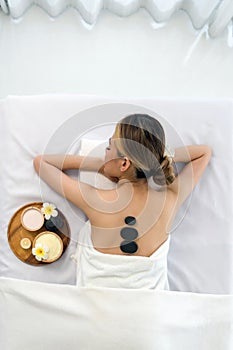 Woman getting spa hot stones massage. Lying on a massage table, relaxing with eyes closed. Spa Thai therapy treatment