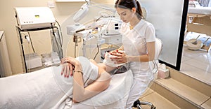 Woman getting spa massage treatment at beauty spa salon. Beautician covering client& x27;s face with towel in beauty