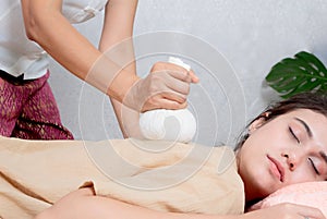 woman getting Thai herbal compress massage in spa