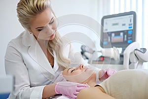 Woman getting treatment with aesthetic dermatology device photo