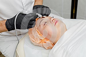 Woman getting ultrasound cavitation face treatment in spa salon