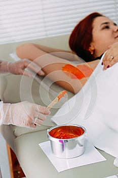 Woman getting wax epilation in salon