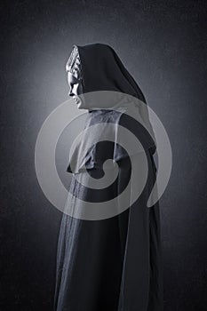 Woman ghost in hooded cloak over dark background