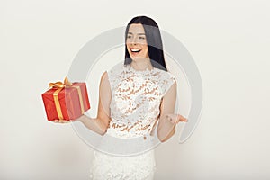 Woman with giftbox in white dress over light background. Beautiful girl with box.
