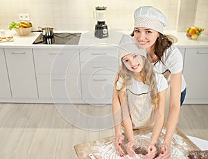 Woman and girl in aprons and chef hats making heart shape.