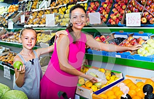 Woman with girl buying apples