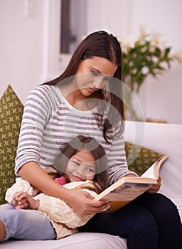 Woman, girl child or book on sofa as reading, imagine or fiction of happy bonding together in home. Mother, daughter or