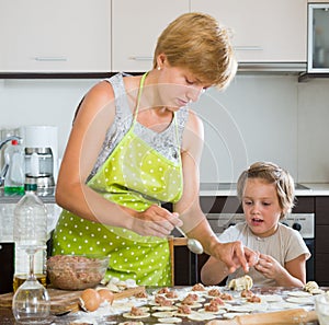 Woman with girl cooking meat dumplings