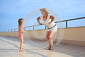 Woman and girl do morning exercise on veranda