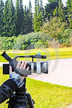 Woman girl filming in the park with a professional camera