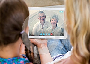 Woman and girl having a video call with senior couple on digital tablet