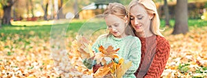 Woman and girl holding autumn yellow leaves