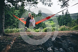 woman with girl kid on hammock mountains on background