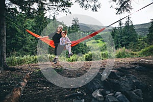 woman with girl kid on hammock mountains on background