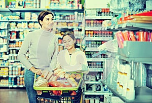 Woman with girl looking for food in supermarket