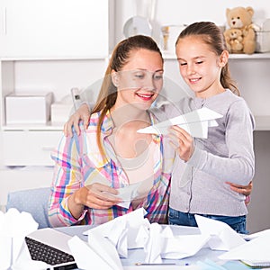 Woman and girl making airplanes of pape