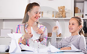 Woman and girl making airplanes of pape