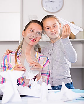 Woman and girl making airplanes of pape