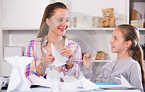 Woman and girl making airplanes of pape