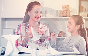 Woman and girl making airplanes of pape