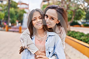 Woman and girl mother and daughter hugging each other at park