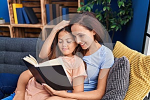Woman and girl mother and daughter reading book at home