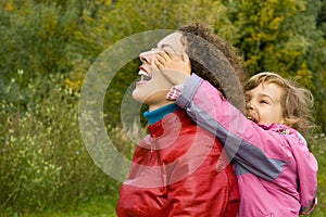 Woman and girl playing in garden, girl closes eyes