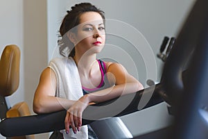 Woman girl resting at the gym on a cross trainer