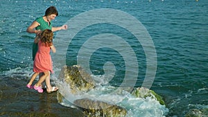 Woman with girl on rocks in waves. Slow Motion