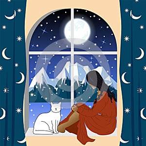 A woman  a girl sits by the window with a cat and looks at the winter mountain landscape. Lonely evening  waiting.