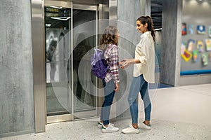 Woman and a girl talking before the closed elevator doors