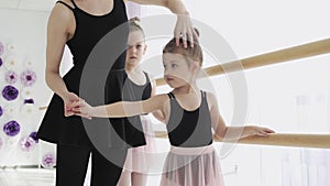 A woman and a girls in a ballet school. Adult ballerina practicing with the little girls and trains Russian classical